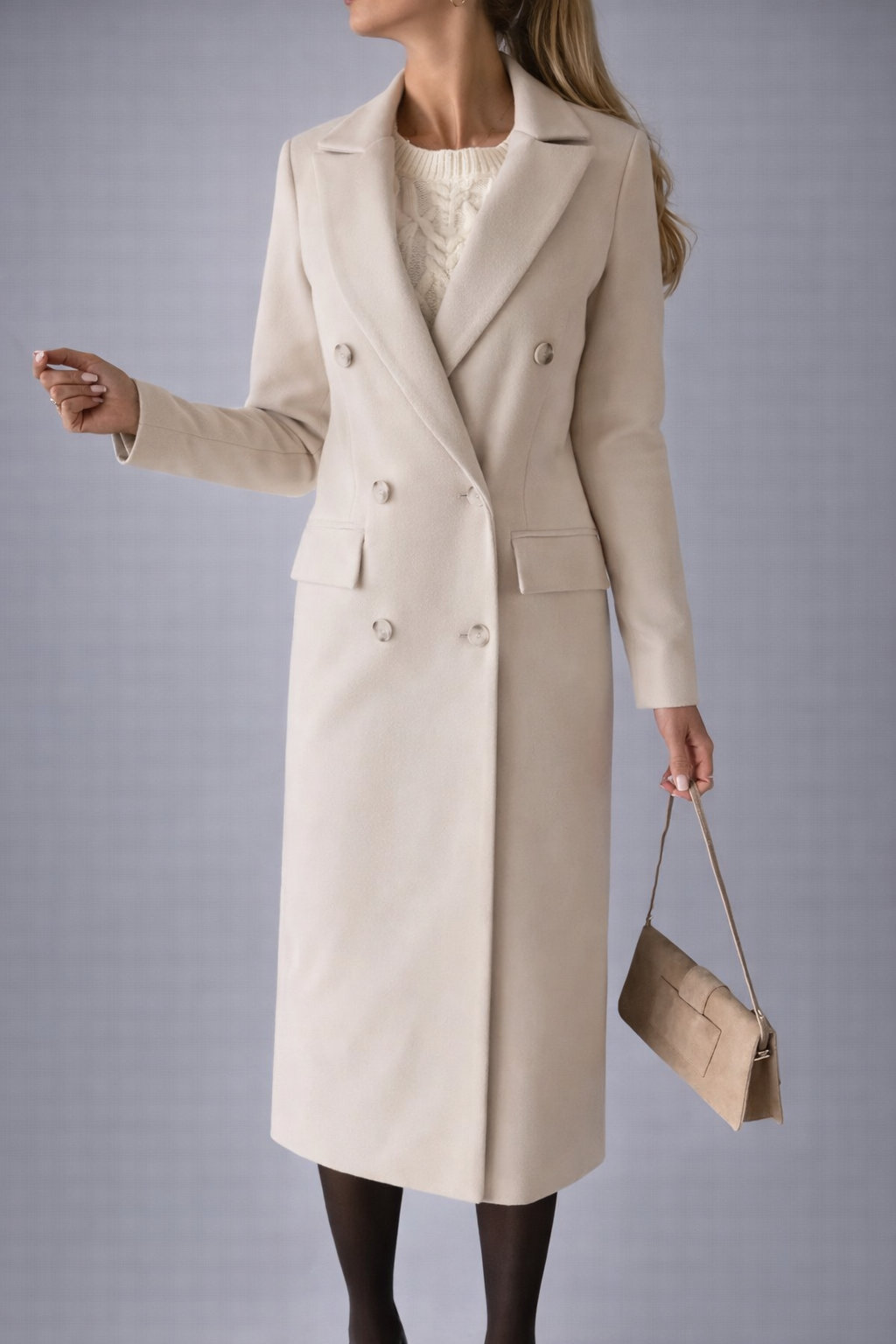 Woman wearing a beige coat and holding a matching handbag against a gray background
