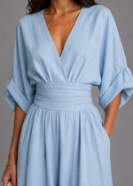 Light blue dress with a V-neck and wide sleeves on a gray background