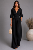 Woman wearing a black dress holding a woven bag against a gray background
