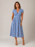 Woman wearing a blue floral dress against a plain background