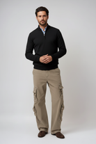 Man wearing a black sweater and beige cargo pants on a white background
