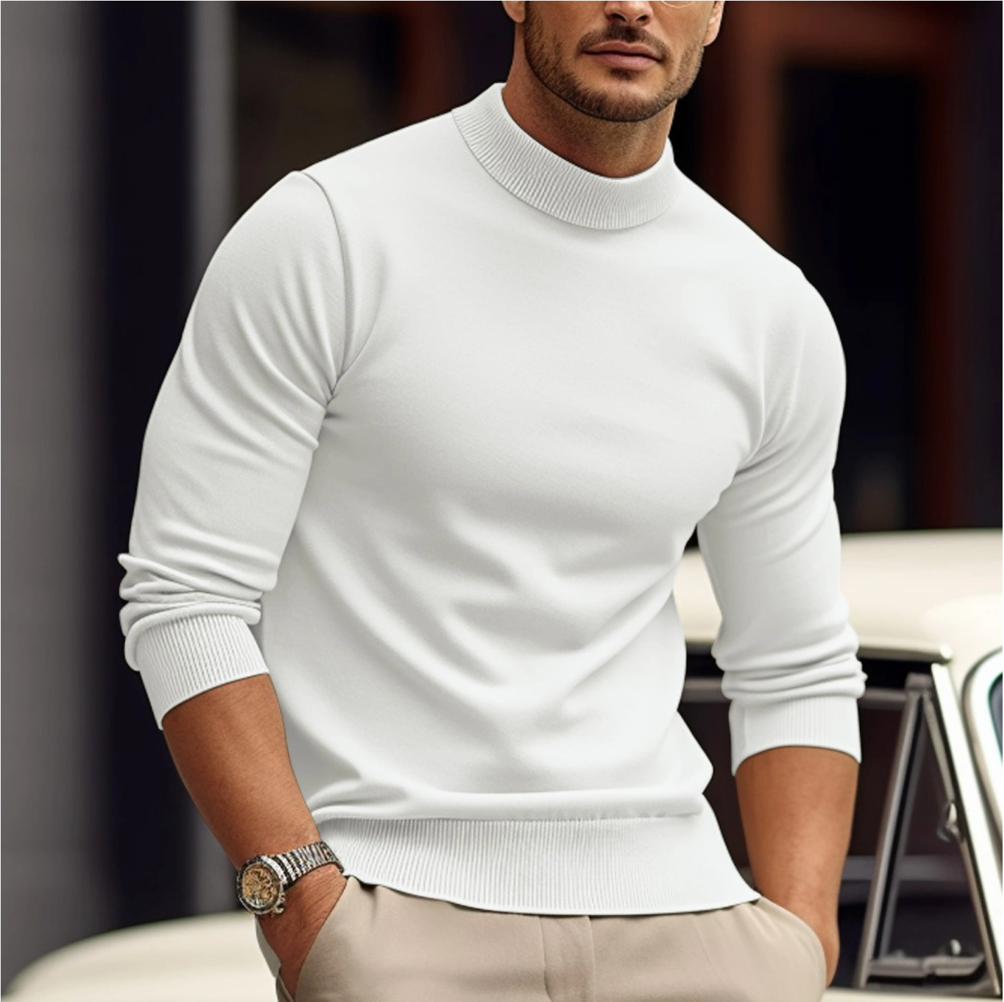 Man wearing a white turtleneck sweater and beige pants, standing outdoors.