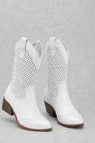 White cowboy boots with perforated design on a gray background