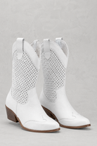 White cowboy boots with studded details on a gray background