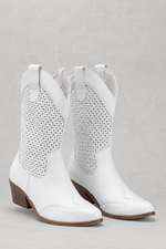 White cowboy boots with studded details on a gray background