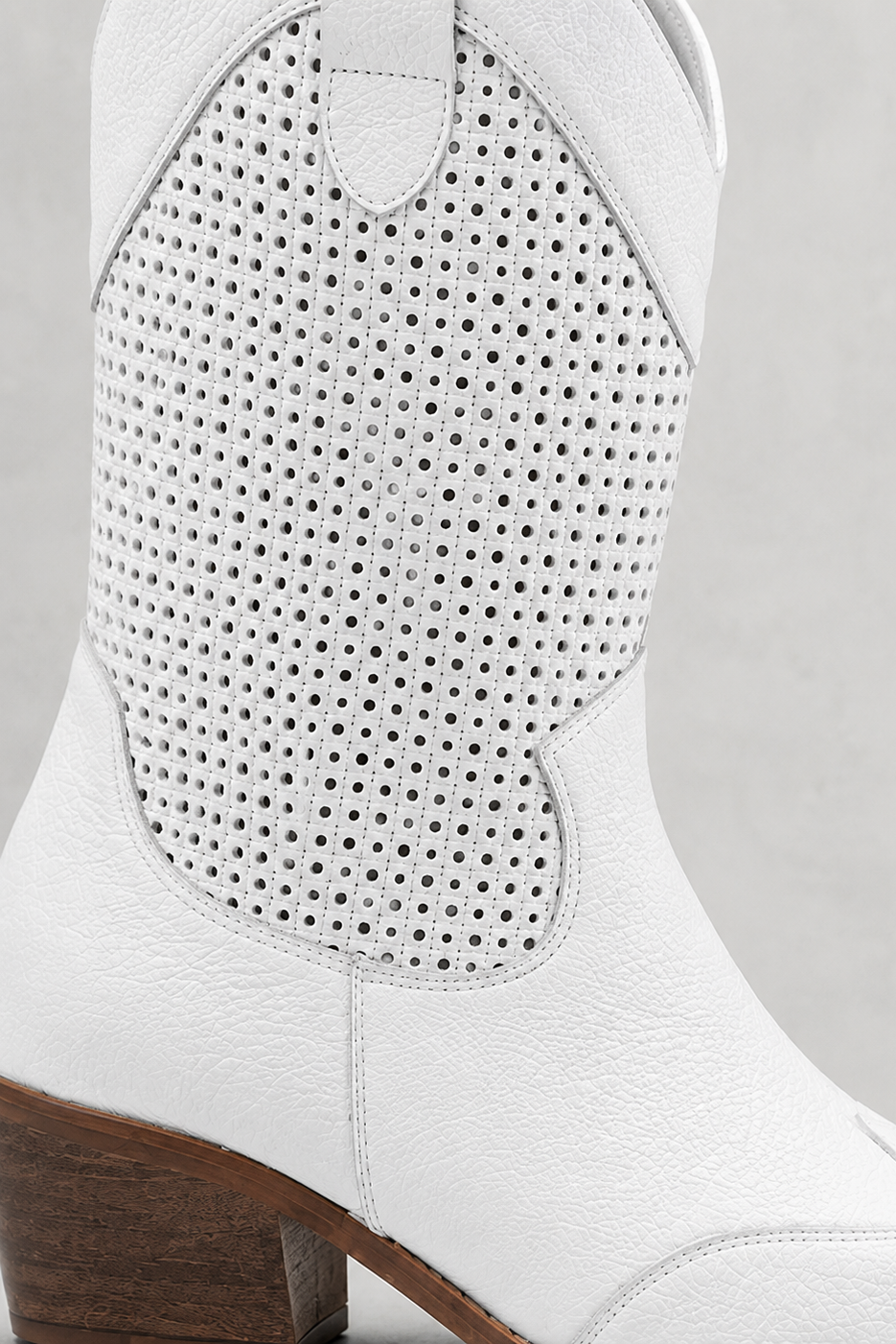 White cowboy boot with perforated design on a light gray background