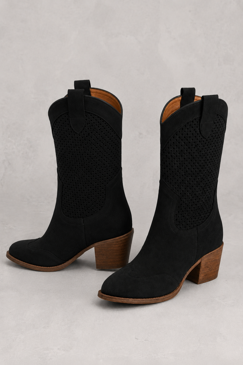 Black cowboy boots with brown soles on a light gray background