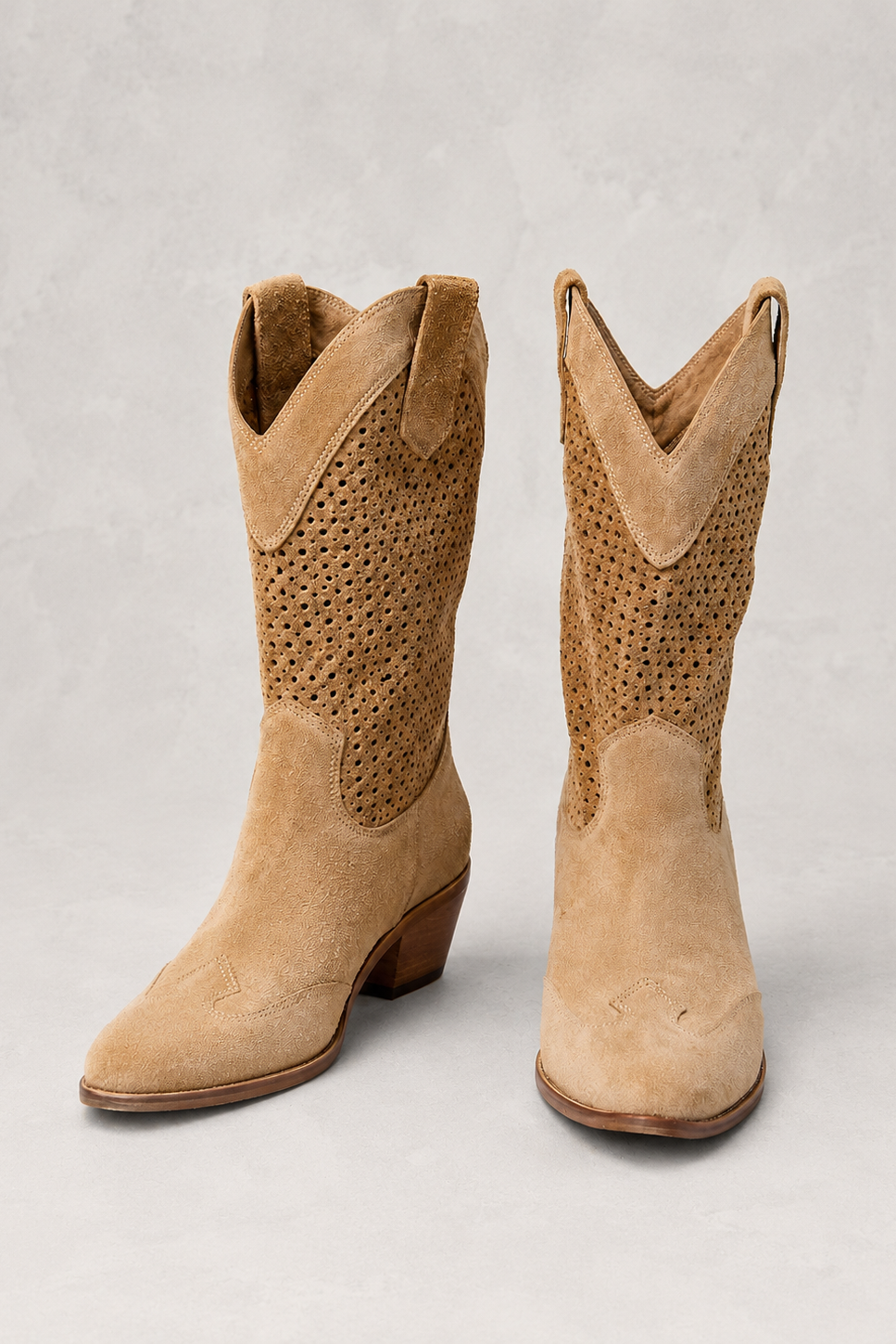 Pair of tan cowboy boots on a light gray background