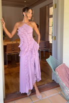 Woman in a lavender one-shoulder dress standing in a doorway.