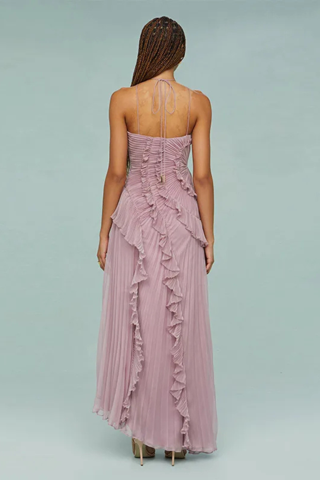 Woman wearing a pink strapless gown with ruffled details on a light gray background