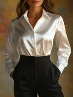 Person wearing a white shirt and black pants against a blurred background