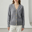 Gray cardigan with gold buttons worn by a person on a white background