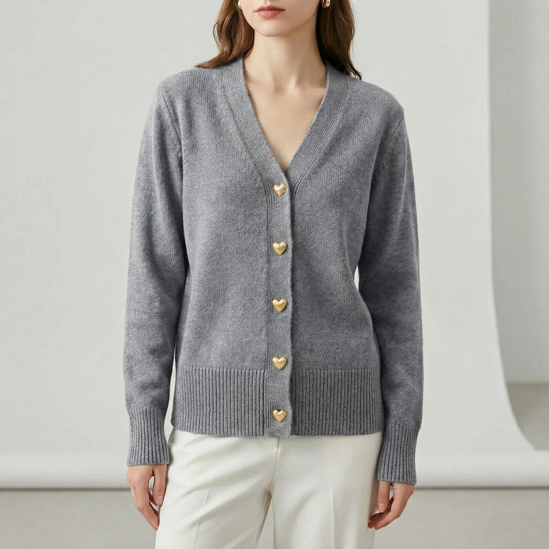 Gray cardigan with gold buttons worn by a person on a white background