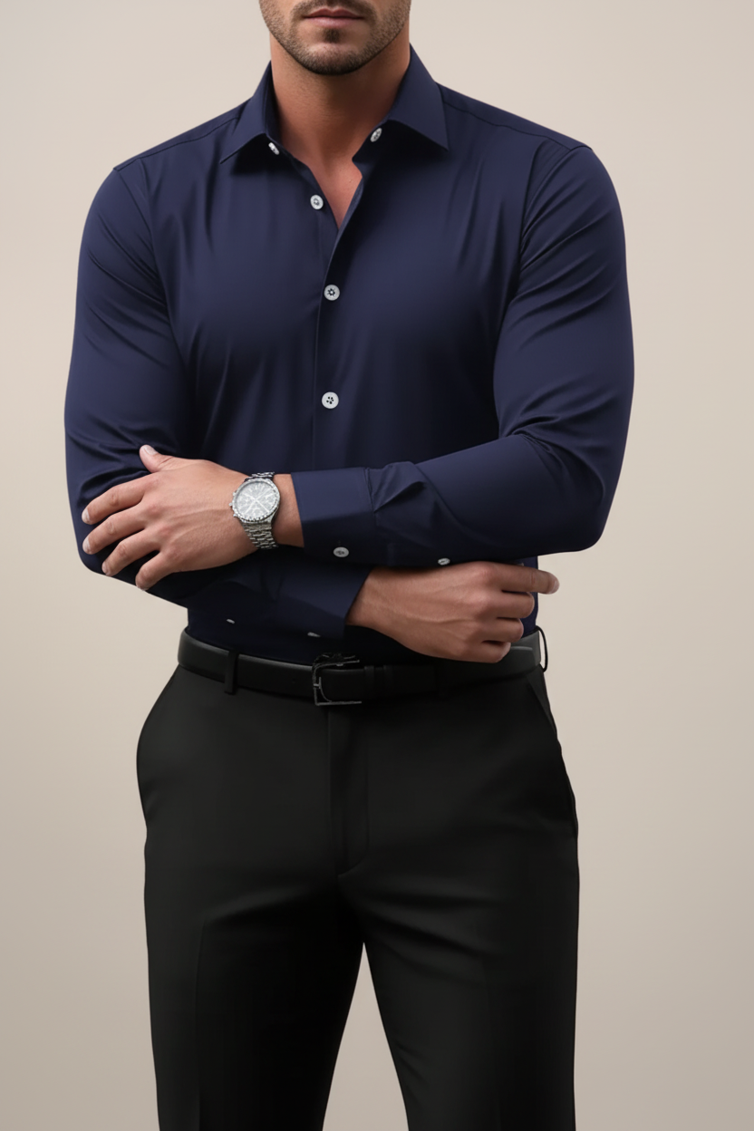 Man wearing a navy blue dress shirt with rolled-up sleeves against a beige background