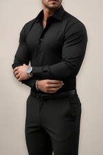 Man wearing a black dress shirt and pants against a beige background