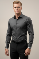 Man wearing a gray dress shirt and black pants against a neutral background