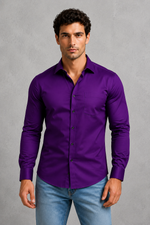 Man wearing a purple shirt and light blue jeans against a gray background