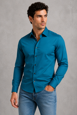Man wearing a blue shirt and jeans against a gray background