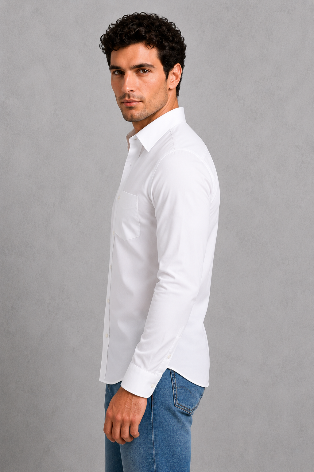 Man wearing a white shirt and blue jeans against a gray background
