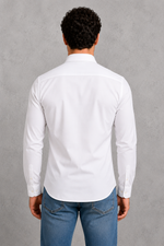 Person wearing a white shirt and blue jeans against a gray background