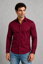 Man wearing a burgundy shirt and blue jeans against a gray background