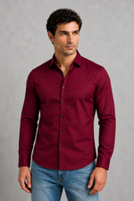 Man wearing a burgundy shirt and blue jeans against a gray background