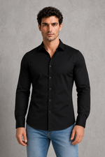 Man wearing a black shirt and blue jeans against a gray background