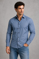 Man wearing a blue shirt and jeans against a gray background