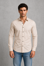 Man wearing a beige button-up shirt and blue jeans against a gray background