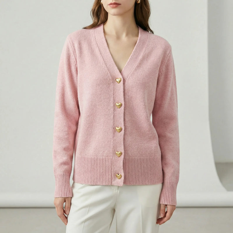 Pink cardigan with gold buttons worn by a person on a white background