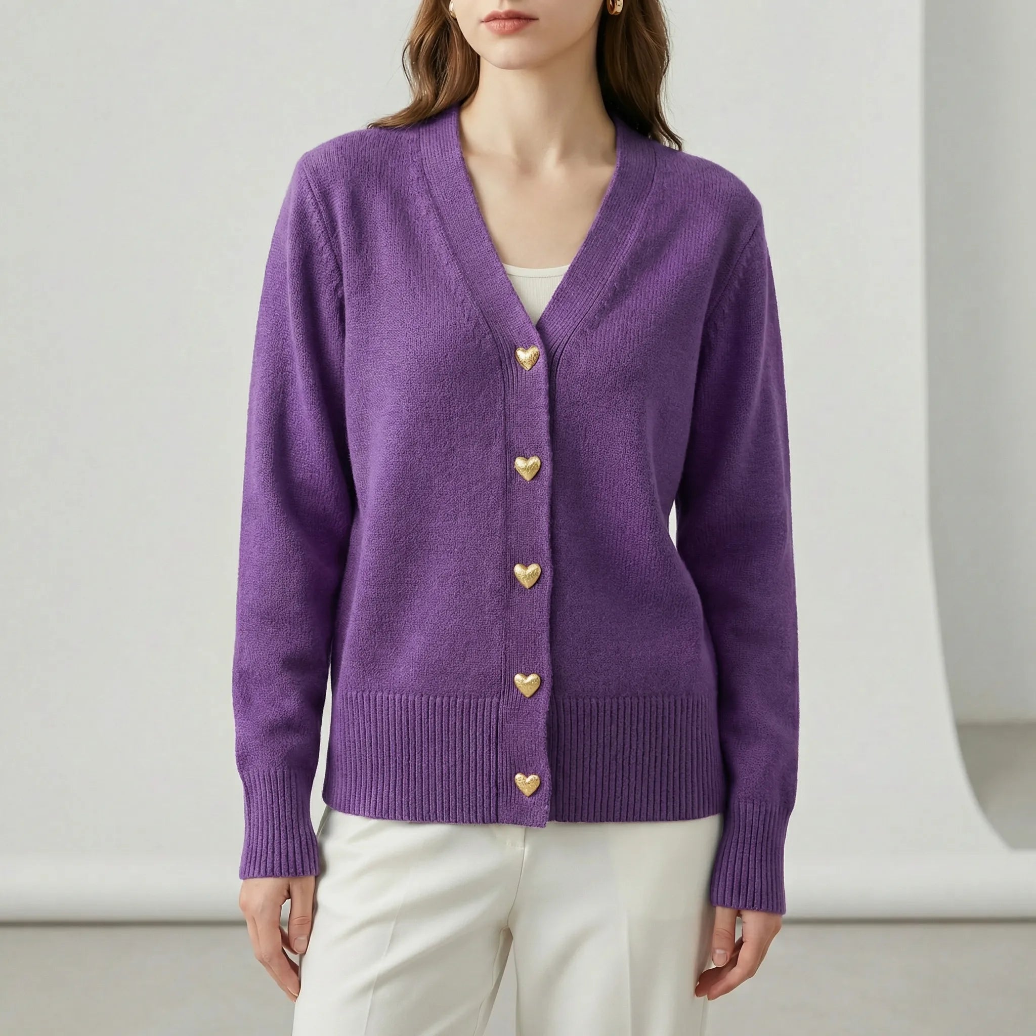 Purple cardigan with gold buttons worn by a person on a white background