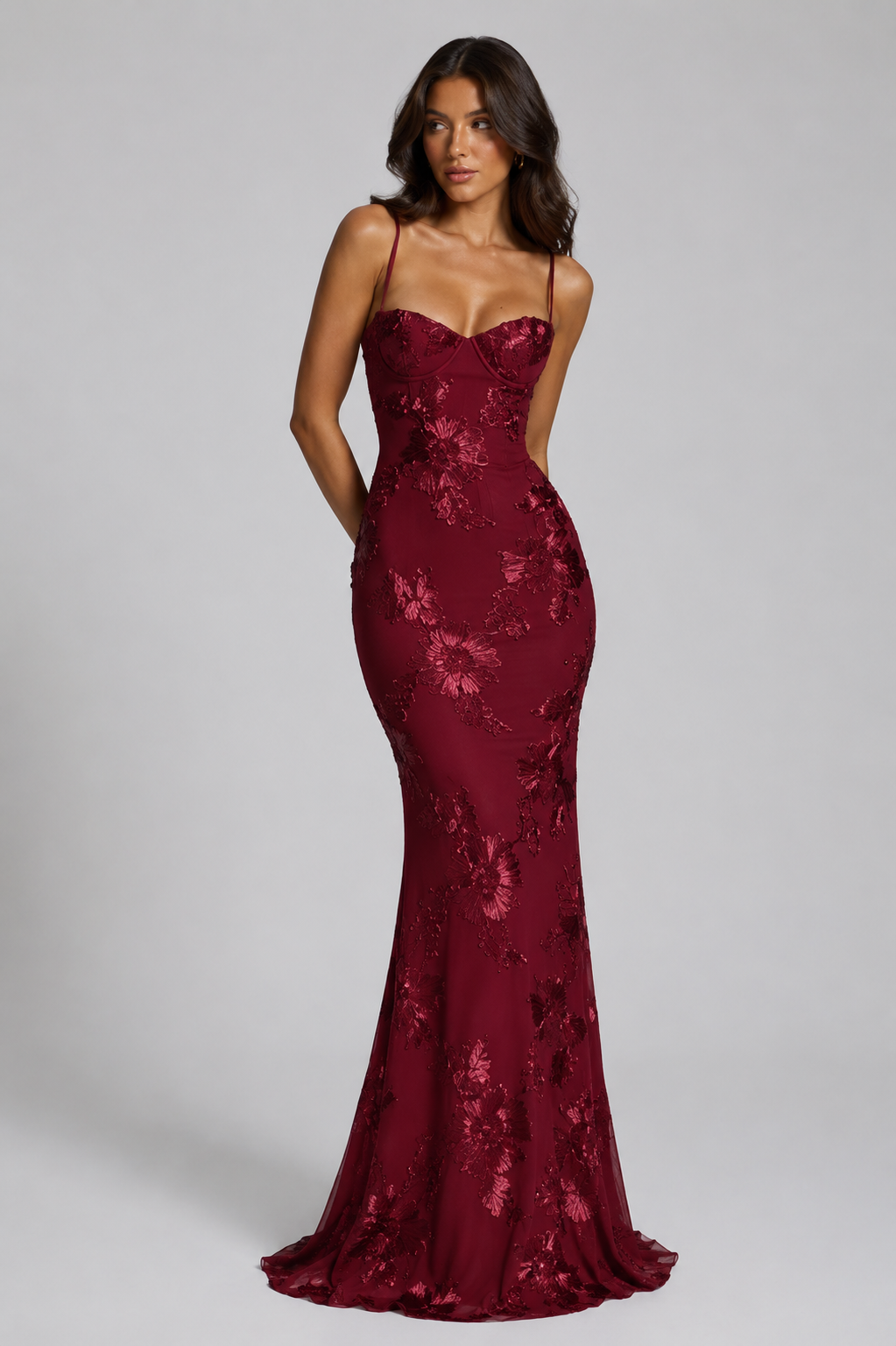 Woman wearing a burgundy lace evening gown on a gray background
