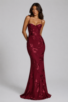 Woman wearing a burgundy lace evening gown on a gray background