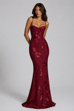 Woman wearing a burgundy lace evening gown on a gray background