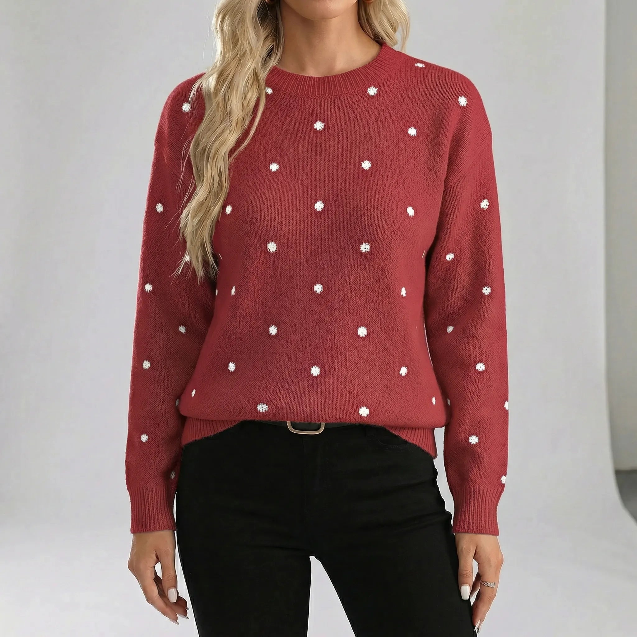 Red sweater with white polka dots worn by a person on a plain background