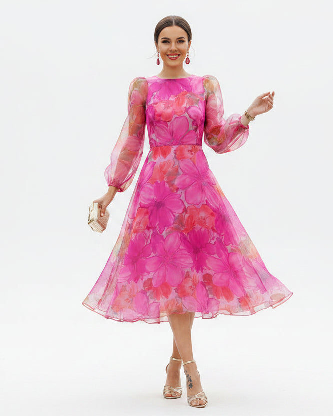 Woman wearing a vibrant pink floral dress standing on a street.