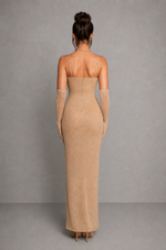 Woman wearing a beige evening gown with sheer sleeves against a gray background