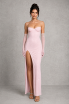 Woman wearing a pink evening gown with sheer gloves against a gray background