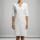 White dress with floral pattern worn by a person on a gray background