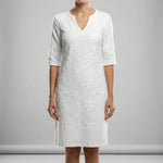 White dress with floral pattern worn by a person on a gray background