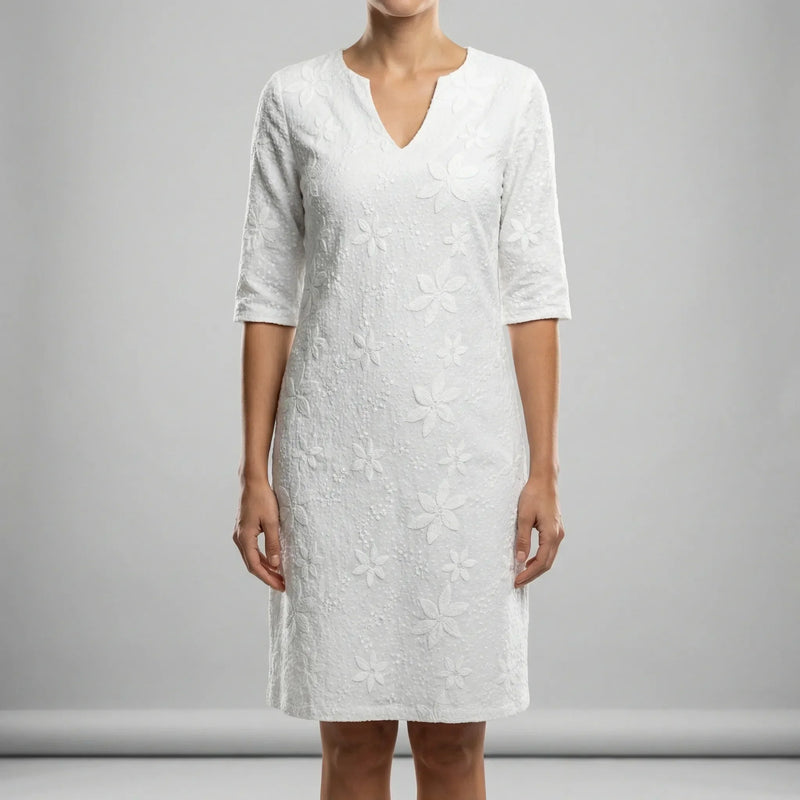 White dress with floral pattern worn by a person on a gray background