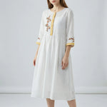 White dress with floral embroidery on a plain background