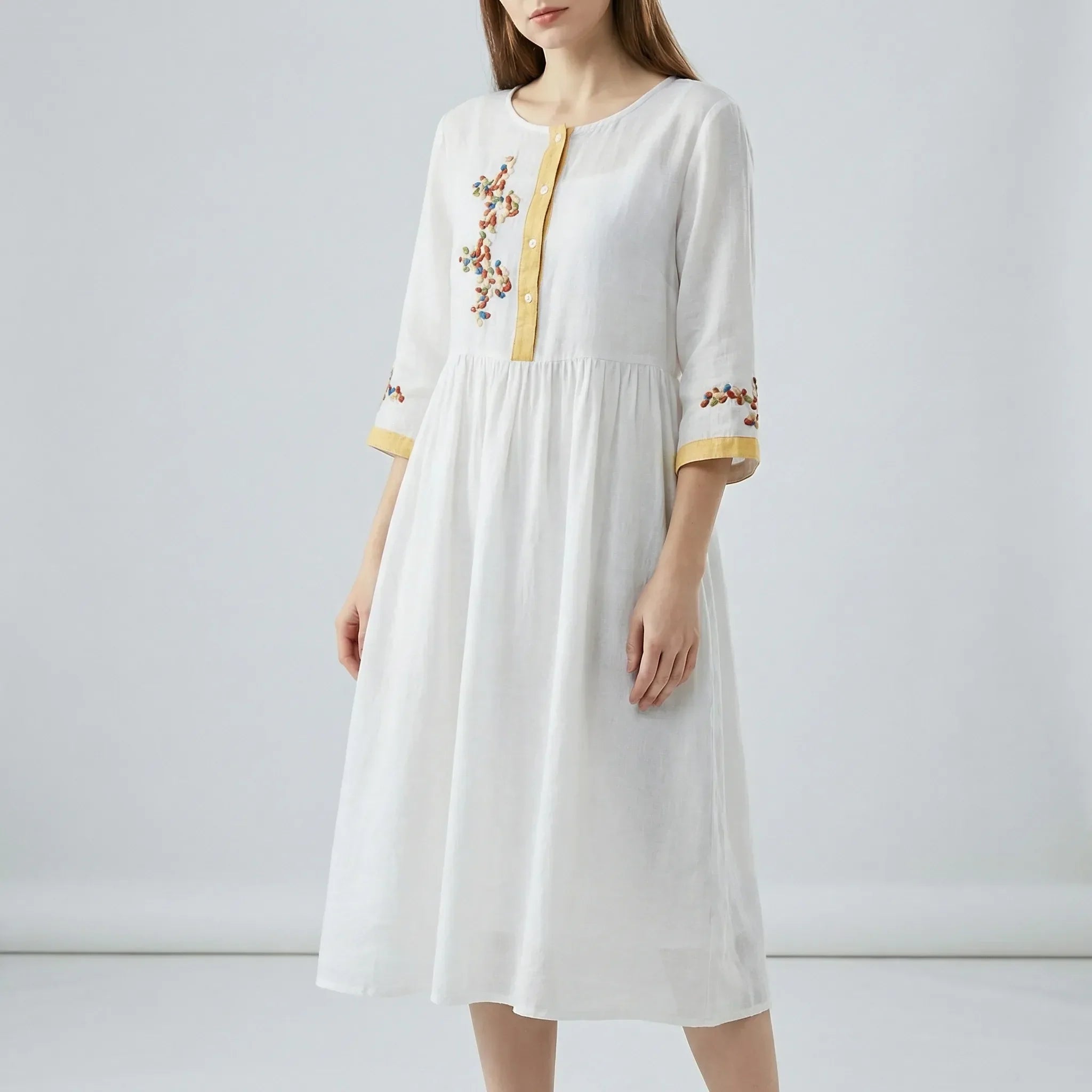 White dress with floral embroidery on a plain background