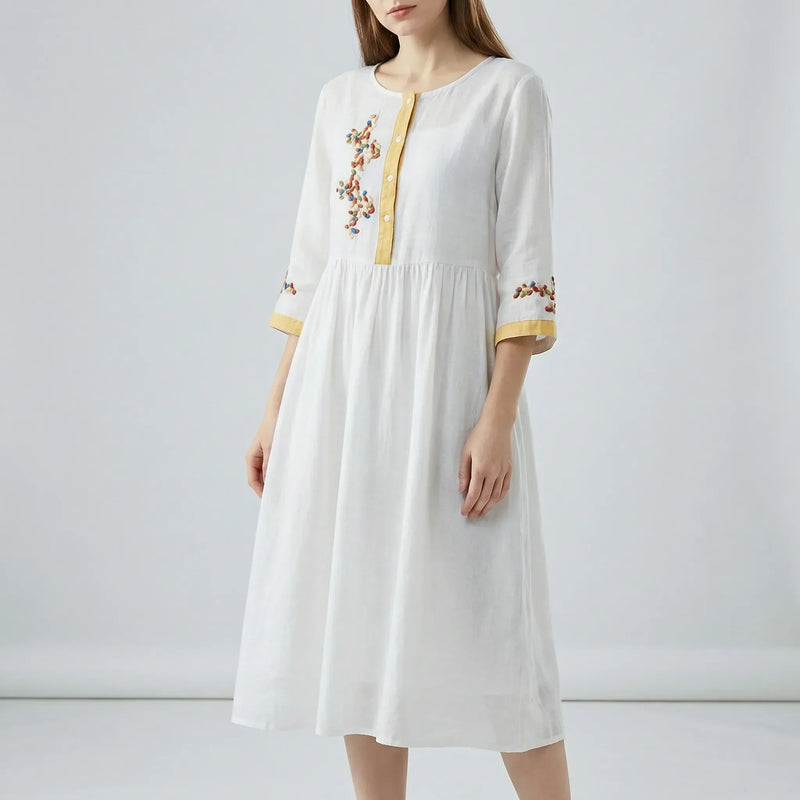 White dress with floral embroidery on a plain background