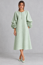 Women’s long dress with 3D floral detailing, round neckline, statement lantern sleeves, button accents and a loose A-line silhouette.