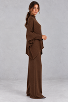 Women’s ribbed knit two-piece set with an asymmetric high-neck jumper, draped crossover hem and matching wide leg trousers.