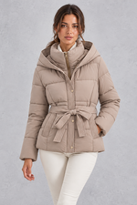 Women’s belted hooded quilted puffer jacket with warm padding, a high neckline, adjustable tie waist and practical side pockets.