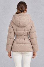 Women’s belted hooded quilted puffer jacket with warm padding, a high neckline, adjustable tie waist and practical side pockets.