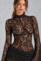 Women’s black sheer lace bodycon dress with long sleeves, elegant draped detailing and a sleek fitted silhouette.