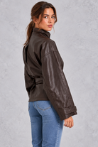 Women’s brown faux leather cropped jacket with a classic lapel collar, long sleeves and an adjustable belted waist.